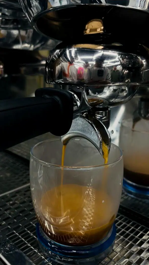 Un expresso coule du porte-filtre