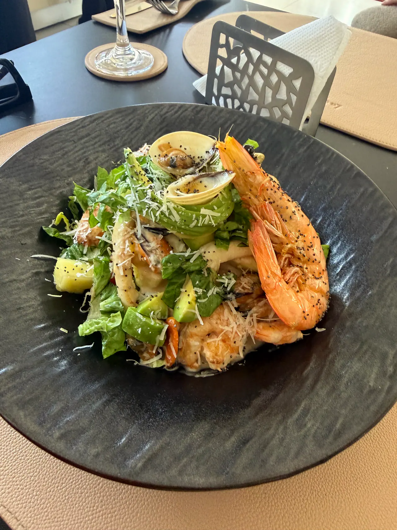 Salade de crevettes et palourdes sur une assiette noire