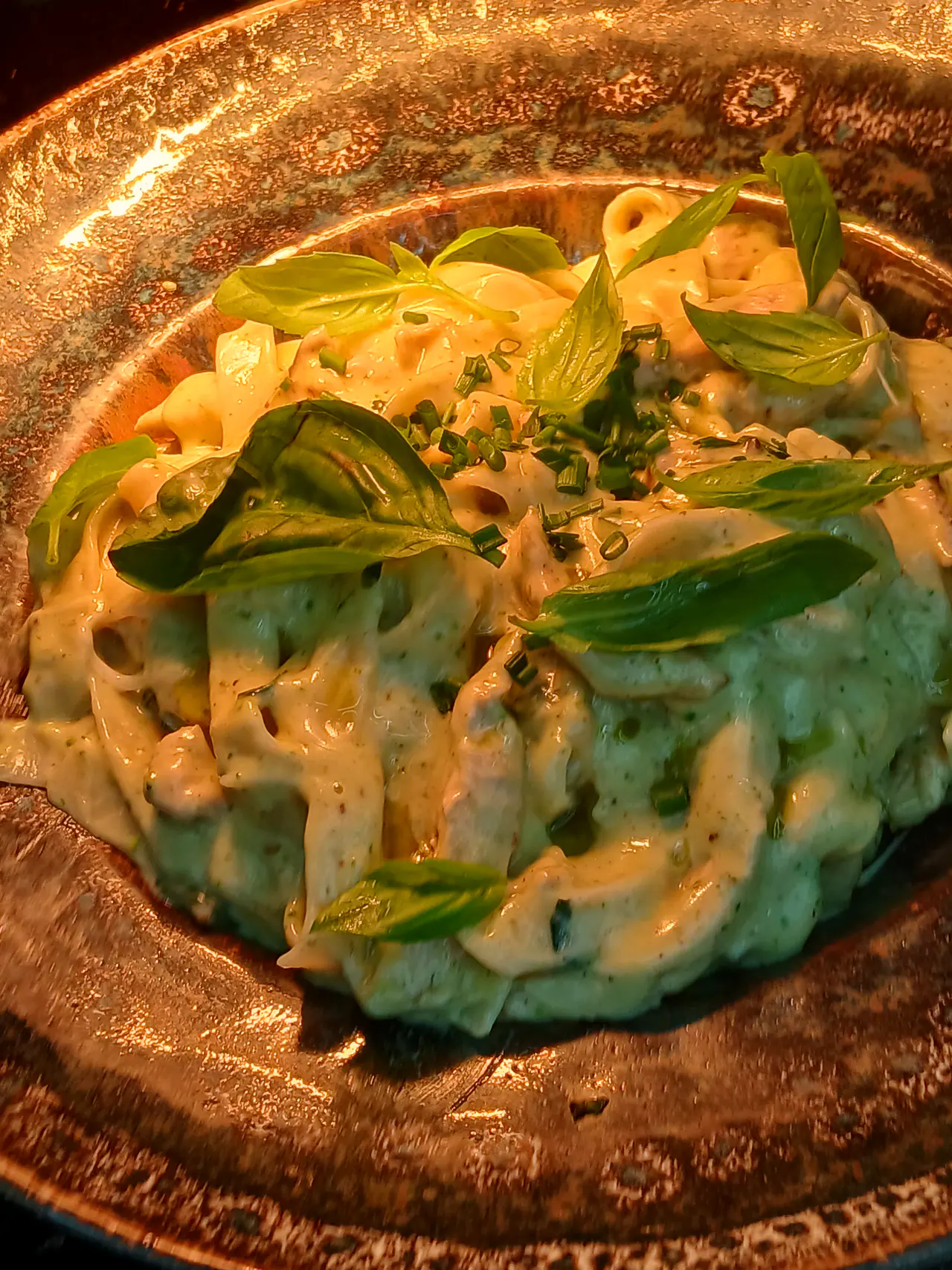 Tagliatelles au basilic sur une assiette en cuivre